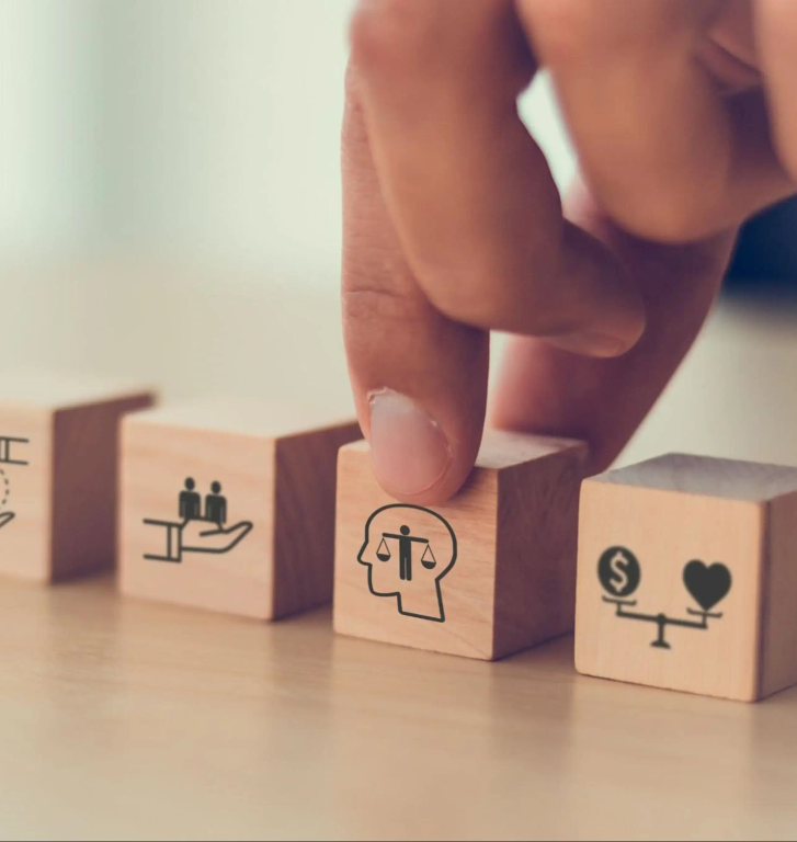 A person holding one of three wooden blocks with symbols on them.