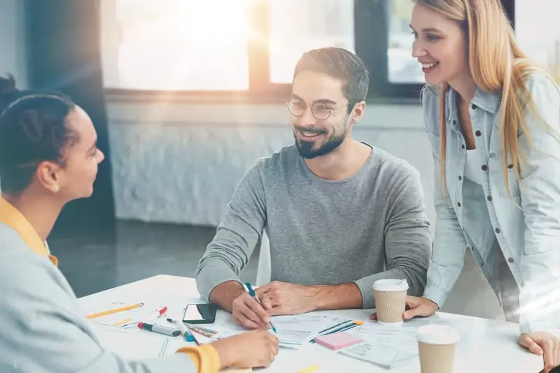 Three smiling people work together around a table.