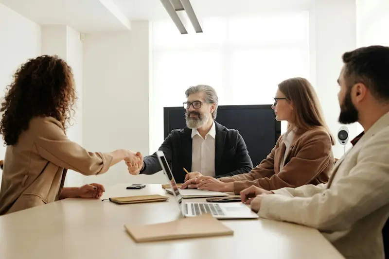 Two interviewers and a candidate engaged in a professional interview at a boardroom table.