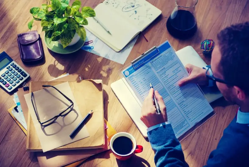 A man completed an application form sat at a table with a cup of coffee.